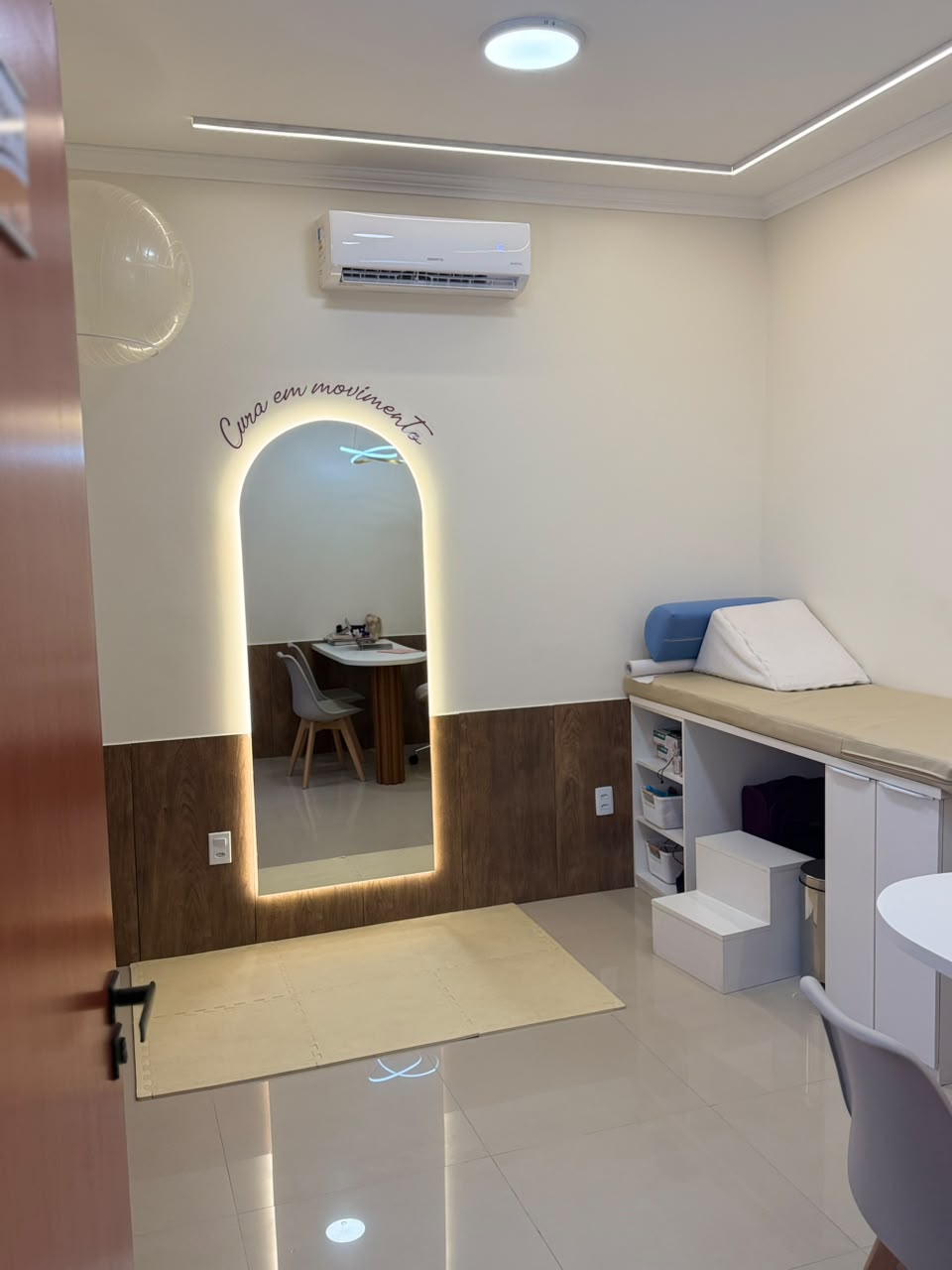 Sala de atendimento do consultório da Dra. Caroline de Oliveira Holanda em Manaus, com maca, espelho iluminado e tapete de exercícios